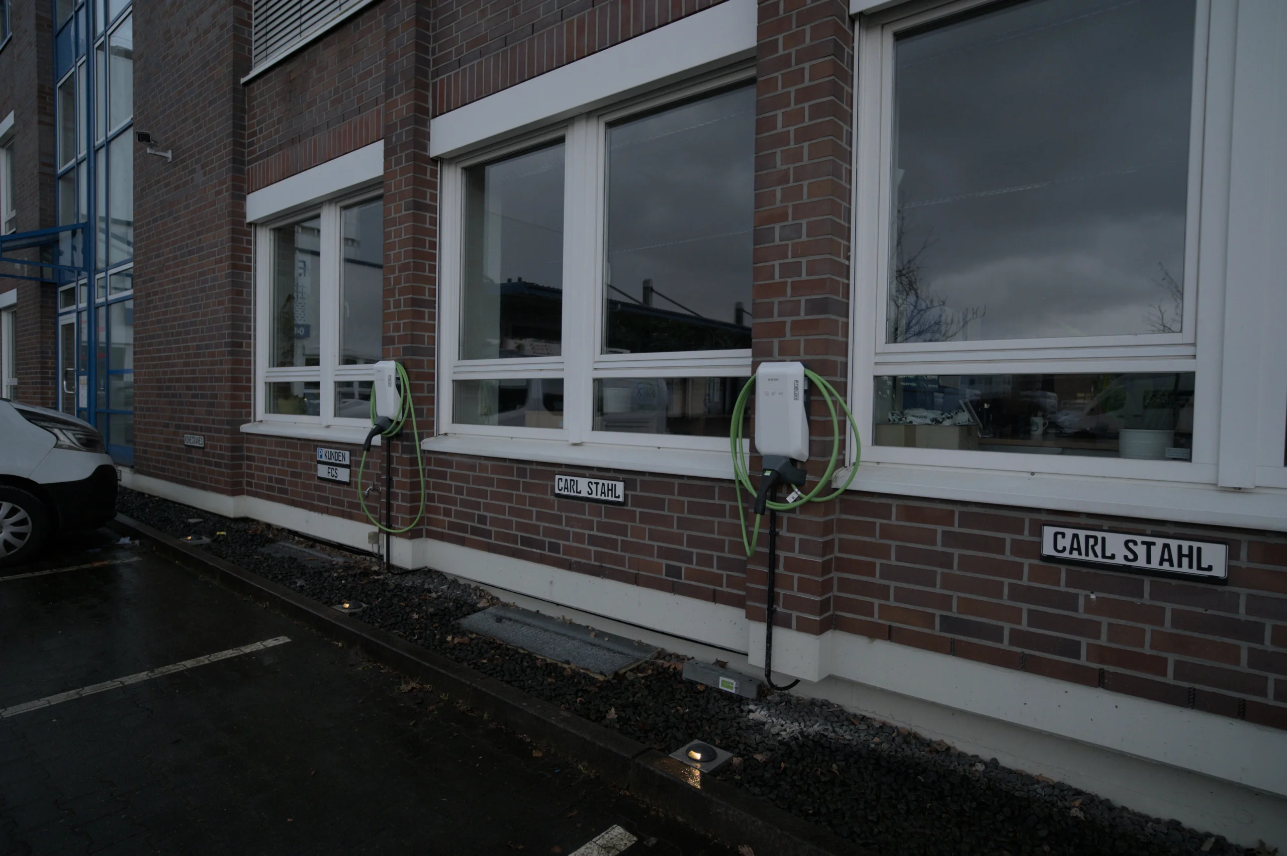 Zwei Wallbox-Ladestationen mit Typ-2-Ladekabeln an der Fassade des Carl-Stahl-Firmengebäudes in Hamburg — Installation und Anmeldung beim Netzbetreiber durch ENELAN GmbH.
