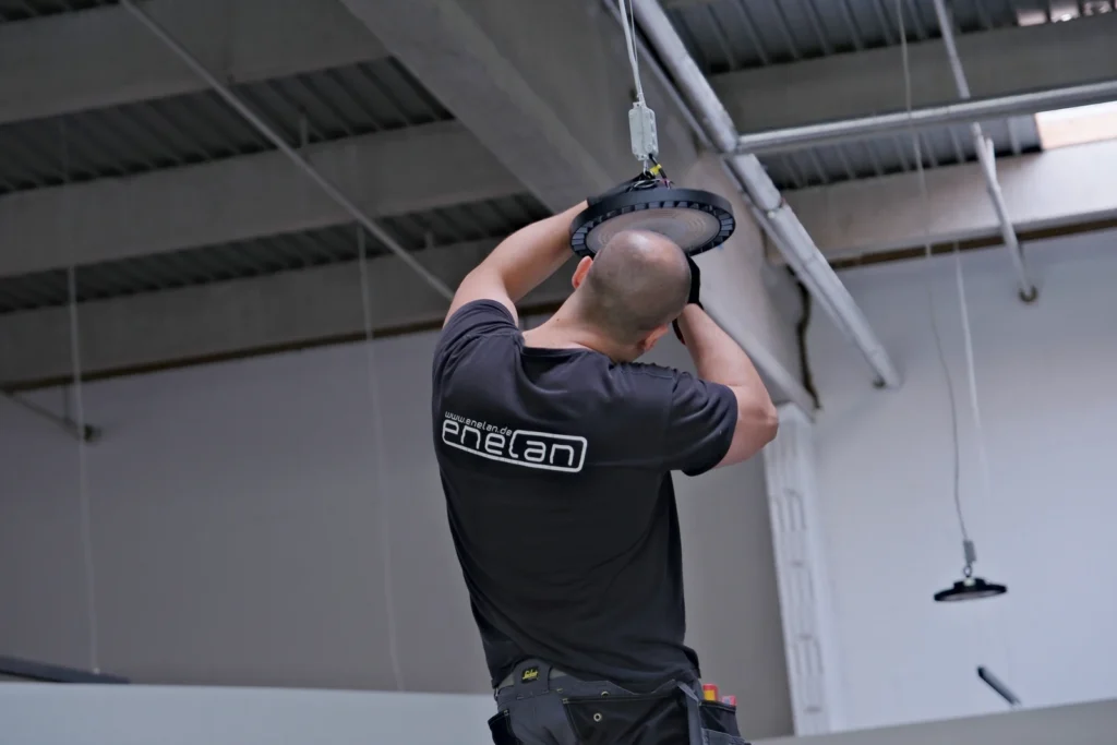 ENELAN-Monteur installiert eine LED-Hallenleuchte unter der Hallendecke
