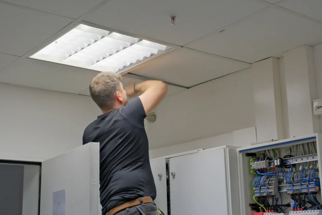 Elektriker setzt ein LED-Panel in die abgehängte Decke ein