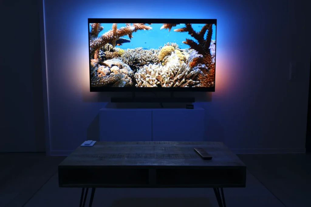 Fernseher mit indirekter Ambient-Beleuchtung im abgedunkelten Wohnzimmer