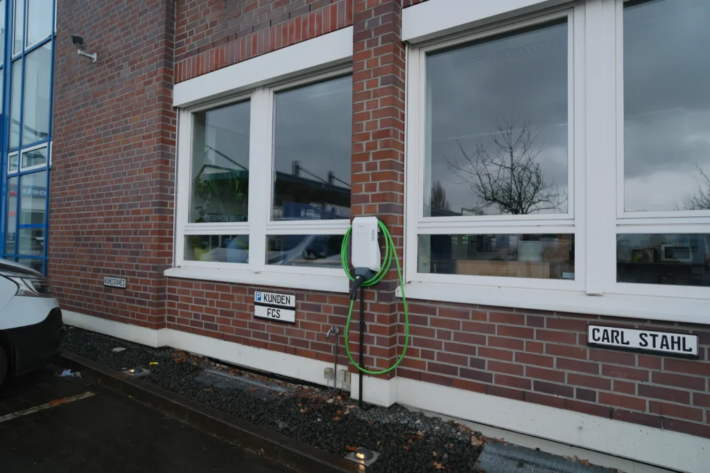 KEBA-Wallbox mit grünem Ladekabel an einer roten Klinkerfassade