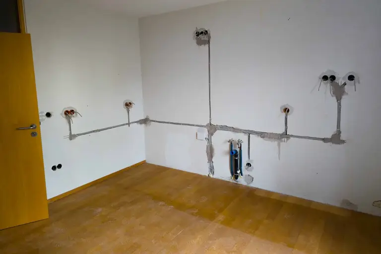 Elektrosanierung: neue Leitungswege und Unterputzdosen in einem leeren Raum vor dem Verputzen